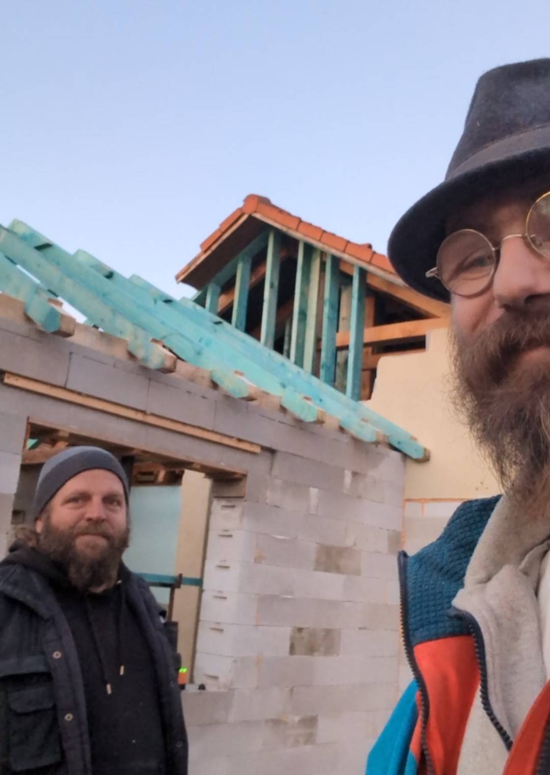 Két ember egy általuk épített nyeregtető előtt